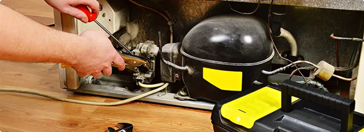 Refrigerator repair technician fixing the compressor and wiring in Whiteside, TN