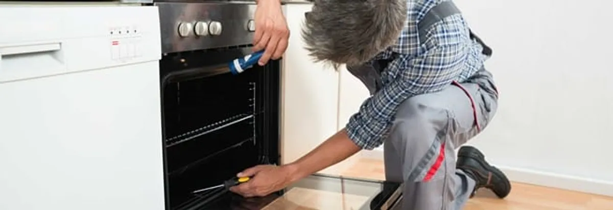 Oven repair technician inspecting and servicing an electric oven in Chattanooga, TN