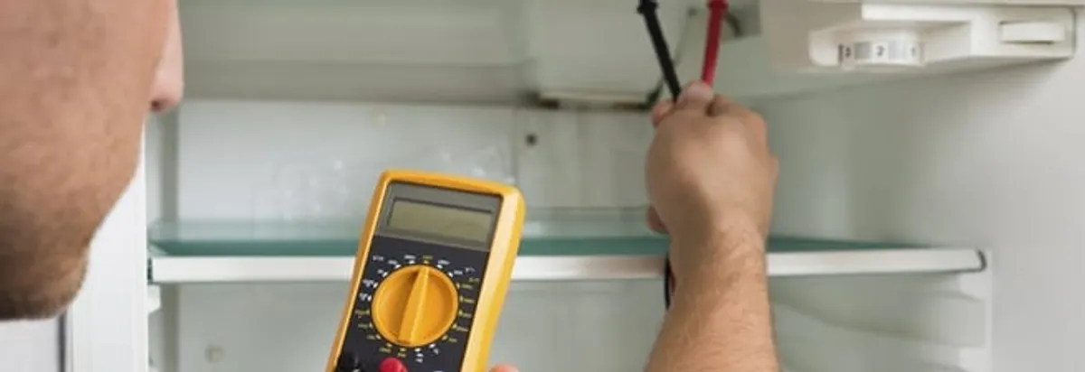 Refrigerator repair technician testing electrical components with a multimeter in Chattanooga, TN